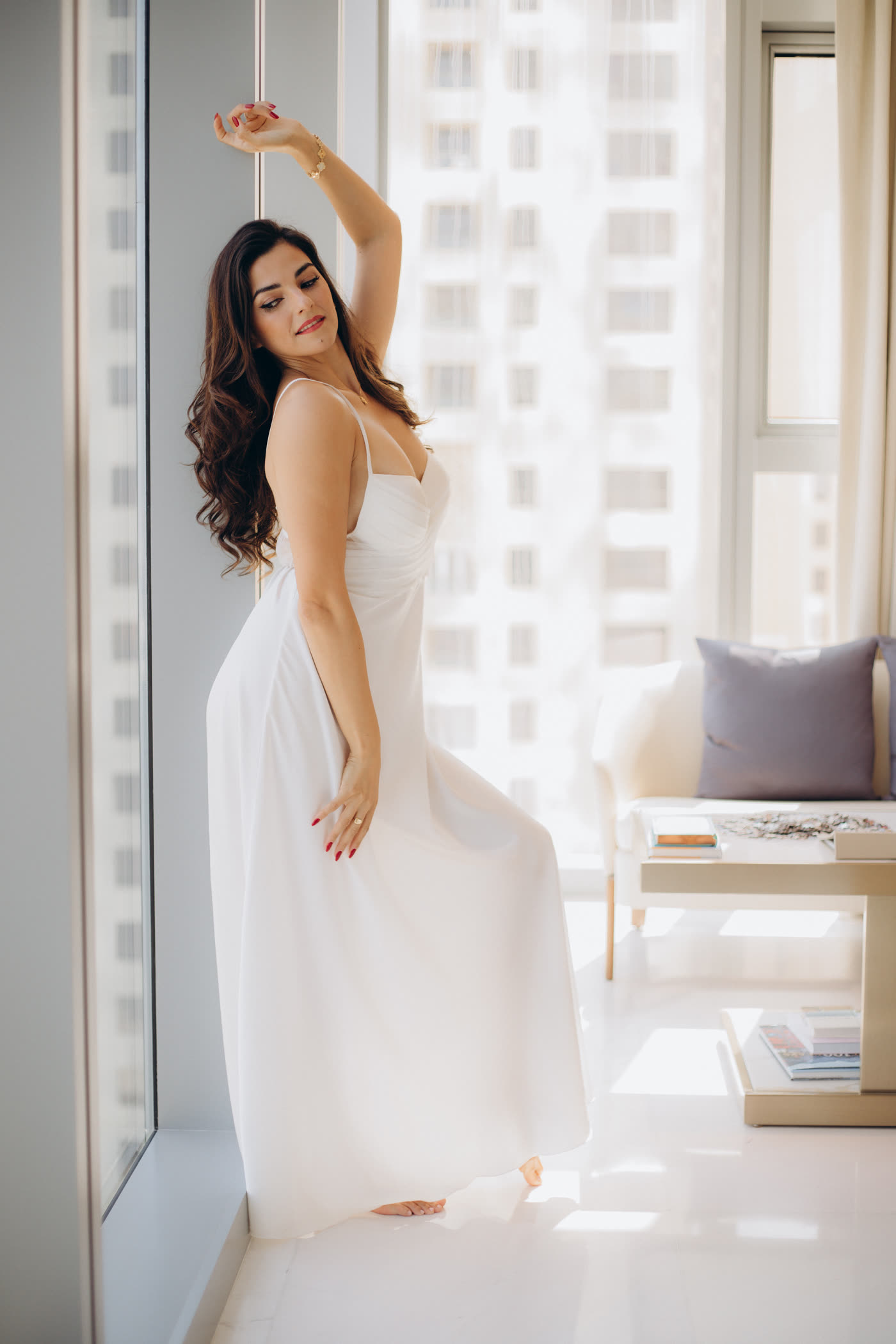 Flo junto a la ventana en vestido blanco